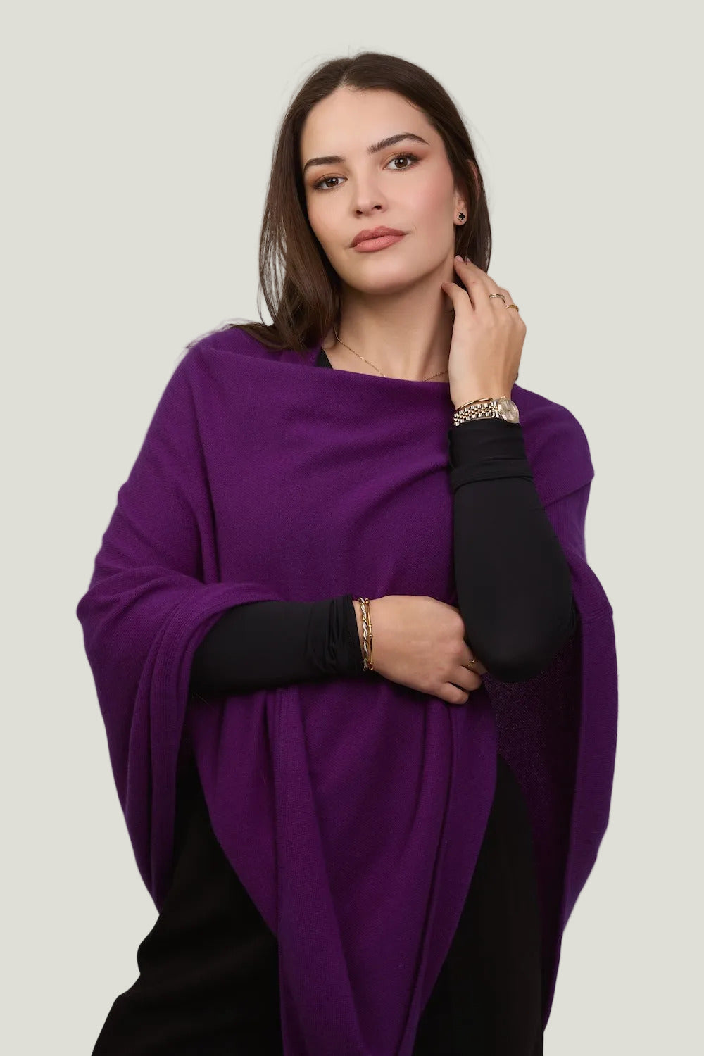 Woman wearing a vibrant purple poncho against a plain background